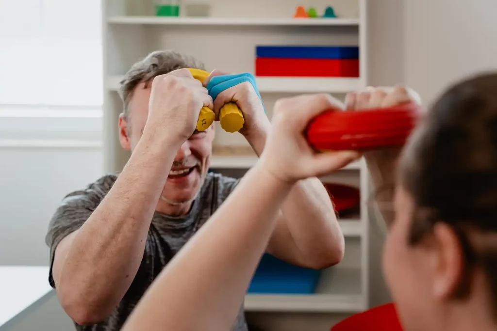 Patient macht aktive Übung mit Gummiring mit Ergotherapeutin