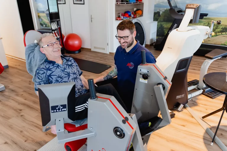 Patient bekommt Einweisung am Trainingsgerät mit Fitnesstrainer im Trainingsraum