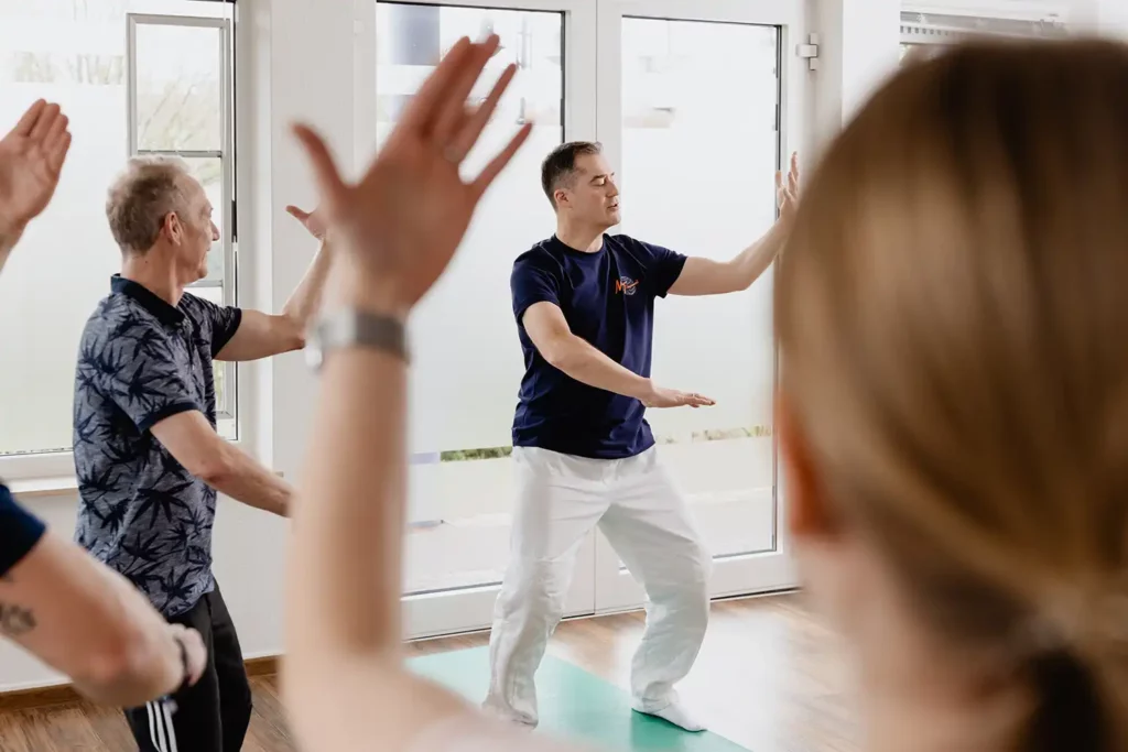 Gruppe von Erwachsenen macht Qigongübungen im Trainingsraum