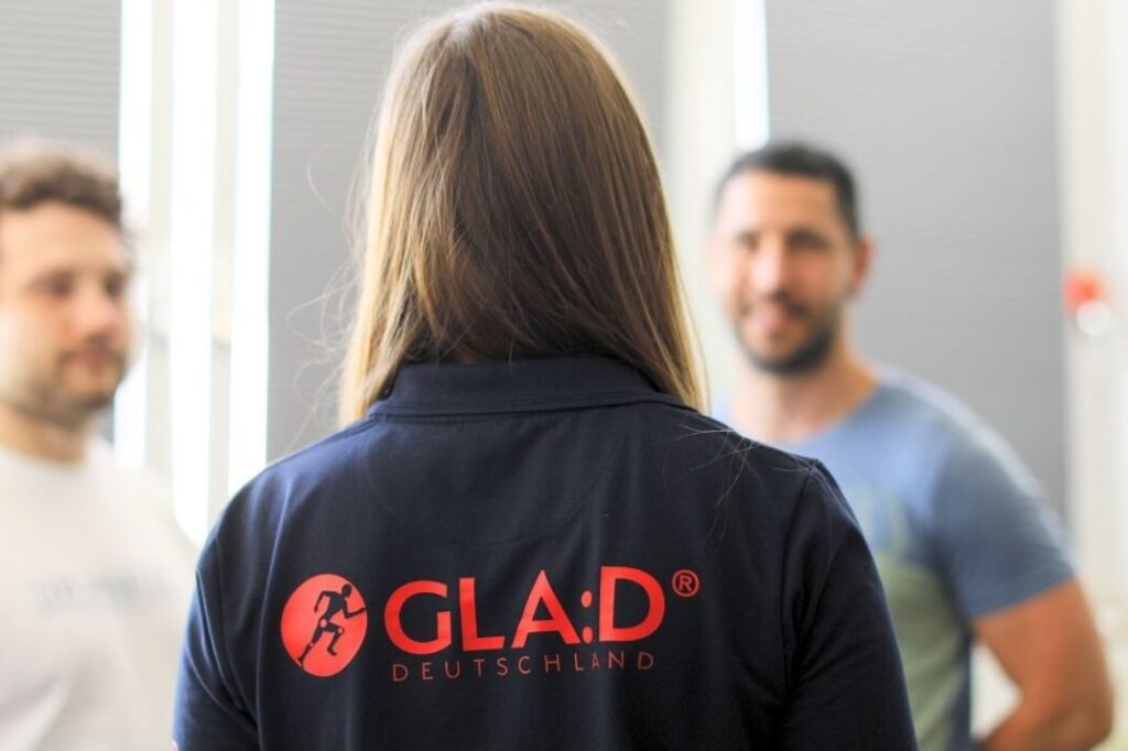 Drei Personen. Hauptperson mit Rückenaufdruch GLA:D zu sehen.